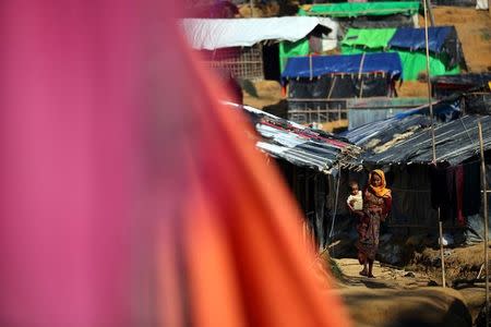 A Rohingya refugee carries a child through Kutupalong refugee camp near Cox's Bazar, Bangladesh, October 23, 2017. REUTERS/Hannah McKay