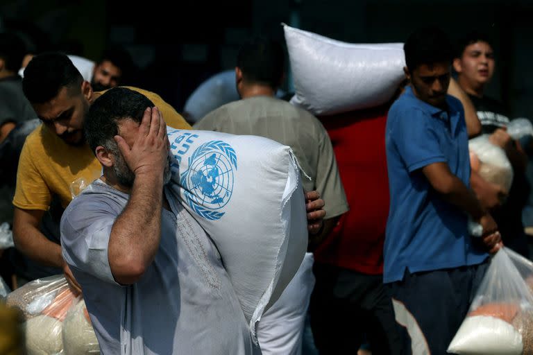 Los palestinos recogen bolsas de legumbres secas en un centro de suministro de ayuda gestionado por la ONU y distribuyen alimentos a los palestinos locales y a las personas desplazadas 