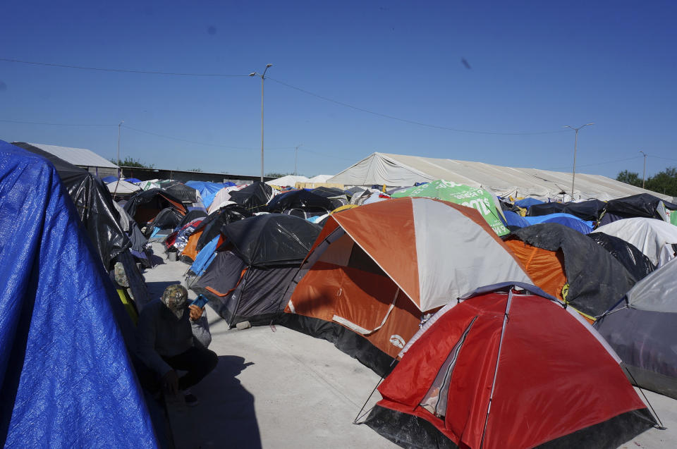 A migrant listens to his phone by his tent in the vast, open-air shelter Senda de Vida 2 in Reynosa, Mexico, on Dec. 15, 2022. The shelter, the second founded by an evangelical pastor in this border city, houses 3,000 migrants from Haiti, Central and South America in tents pitched on concrete or rough gravel, providing only the most essential care but security from the cartels that prey on migrants left outside. (AP Photo/Giovanna Dell'Orto)