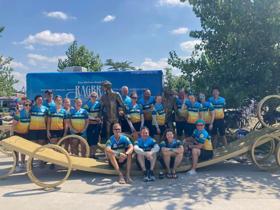 Rachel Kaul and members of her Team Legacy celebrate the life of her father, RAGBRAI co-founder Donald Kaul, during RAGBRAI 50 in 2023 with a visit to the RAGBRAI founders statue in Des Moines' Water Works Park.