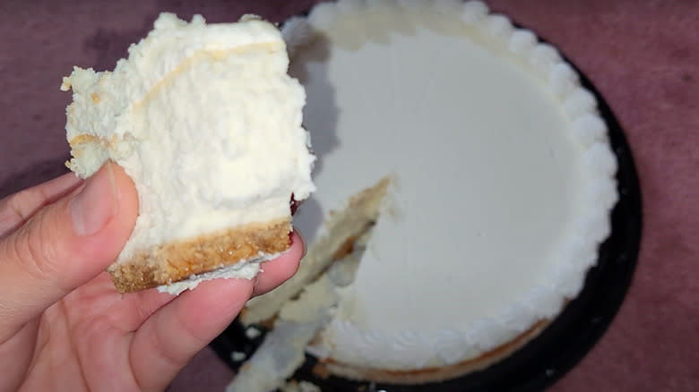 person holding slice of Costco white cake with cheescake filling 