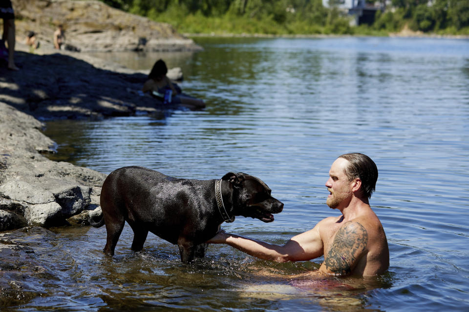 Justin Swanner and his dog Havoc swim in the Clackamas River to escape from the heat during a record setting heat wave in Oregon City, Ore., Sunday, June 27, 2021. Yesterday set a record high for the day with more records expected today. (AP Photo/Craig Mitchelldyer)