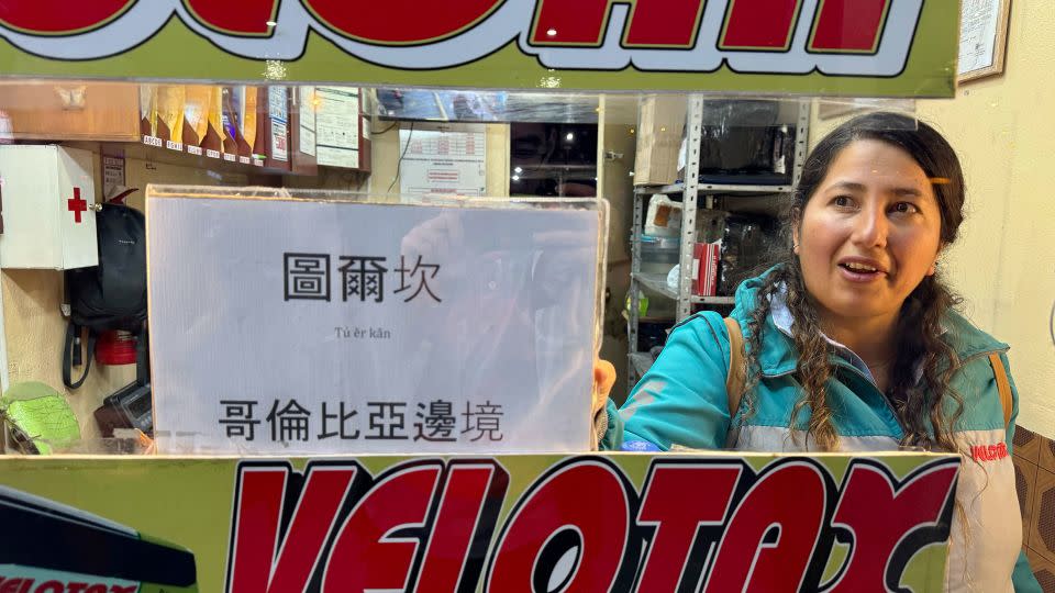 A ticket agent in Quito holds up a sign written in Chinese for the bus to "Tulcan at the Colombian border." - Yong Xiong/CNN