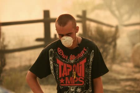 Alex Thurman, 20, stands in front of a smoldering field as the Erskine Fire burns near Weldon, California, U.S. June 24, 2016. Thurman said he thinks the fire destroyed his neighboring home. REUTERS/Noah Berger