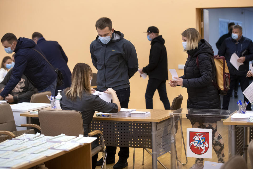 Lithuania's wearing face masks to protect against coronavirus, at a polling station during the early voting in the second round of a parliamentary election in Vilnius, Lithuania, Thursday, Oct. 22, 2020. Lithuanians will vote in the second round of a parliamentary election on upcoming Sunday during the rise in the incidence of coronavirus infection in the country. (AP Photo / Mindaugas Kulbis)