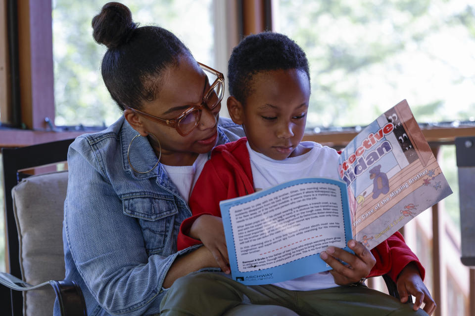 Adriane Burnett reads to her son Karter Robinson on Saturday, April 14, 2024 in Birmingham, Ala. Women's participation in the American workforce has reached a high point, but challenges around child care are holding back many working class parents. When women without college degrees face an interruption in child care arrangements – whether it's at a relative's home, a preschool or a daycare center – they are more likely to have to take unpaid time or to be forced to leave their jobs altogether, according to an Associated Press analysis. (AP Photo/Butch Dill)