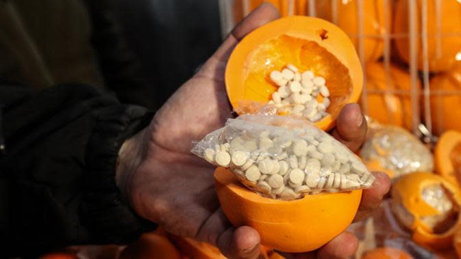 Seorang pria menunjukkan jeruk palsu berisi pil Captagon di Pelabuhan Beirut, Lebanon, 29 Desember 2021. Bea Cukai Lebanon menyita sembilan juta pil Captagon dalam jeruk palsu yang ditujukan ke salah satu negara Teluk. (ANWAR AMRO/AFP)