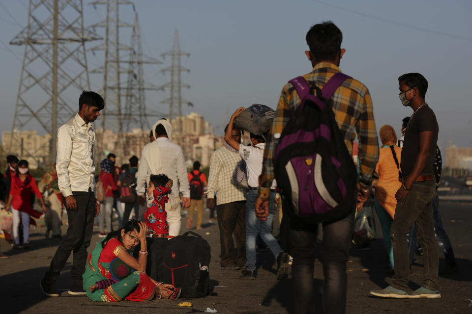 In this Saturday, March 28, 2020, file photo, an Indian migrant family waits for transportation to their village following a lockdown amid concern over spread of coronavirus in New Delhi, India. Over the past week, India’s migrant workers - the mainstay of the country’s labor force - spilled out of big cities that have been shuttered due to the coronavirus and returned to their villages, sparking fears that the virus could spread to the countryside. It was an exodus unlike anything seen in India since the 1947 Partition, when British colothe subcontinent, with the 21-day lockdown leaving millions of migrants with no choice but to return to their home villages. (AP Photo/Altaf Qadri, File)