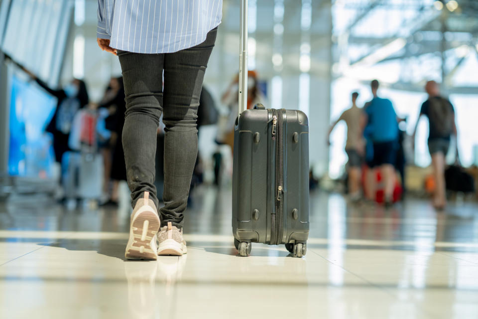 Someone walking through an airport with a suitcase