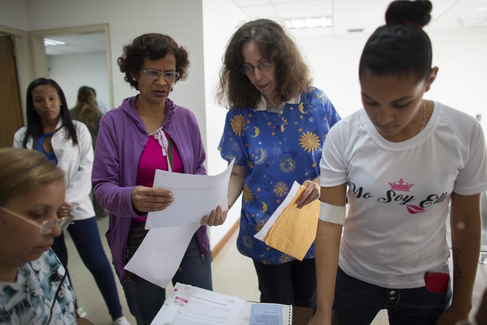 In this photo taken July 25, 2019, Dr. Saturnina Clemente, center, gives instructions to assistants at a small clinic in the Caucaguita neighborhood on the outskirts of Caracas, Venezuela. Clemente is armed with one of Venezuela's most sought-after commodities: Hormonal implants to prevent pregnancy. "It's a sense of impotency, of frustration," she says. "You see that it's not enough, that the demand is much higher." (AP Photo/Ariana Cubillos)