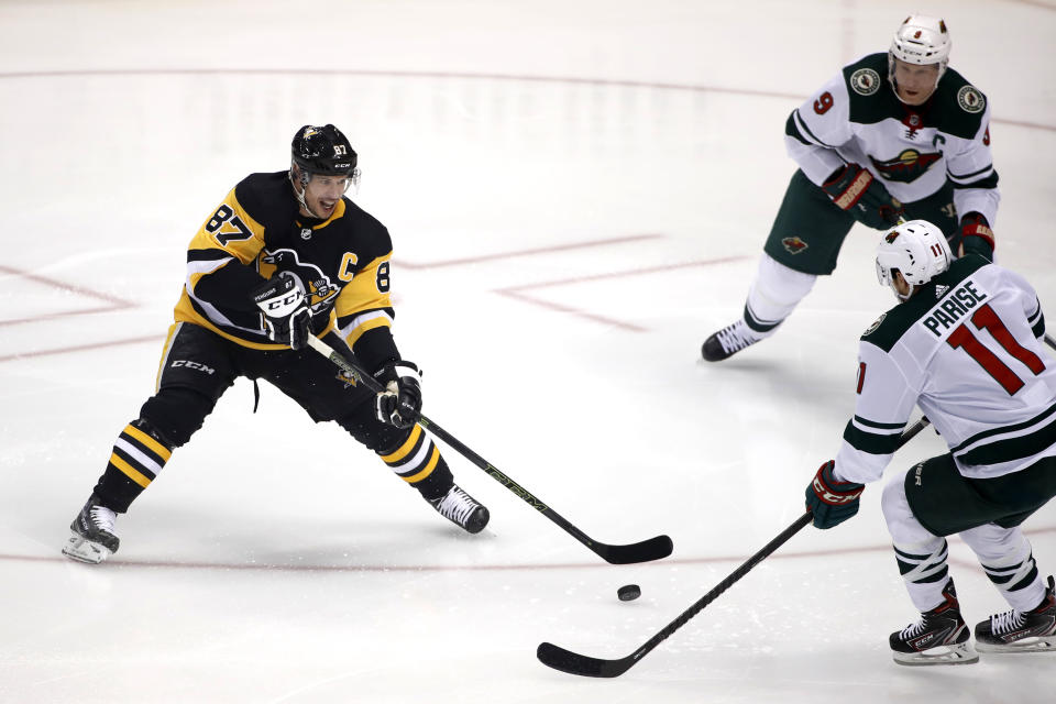 Pittsburgh Penguins' Sidney Crosby (87) gets off a pass with Minnesota Wild's Zach Parise (11) and Mikko Koivu (9) defending during the first period of an NHL hockey game in Pittsburgh, Tuesday, Jan. 14, 2020. Crosby hadn't played since undergoing abdominal surgery on Nov. 14. (AP Photo/Gene J. Puskar)