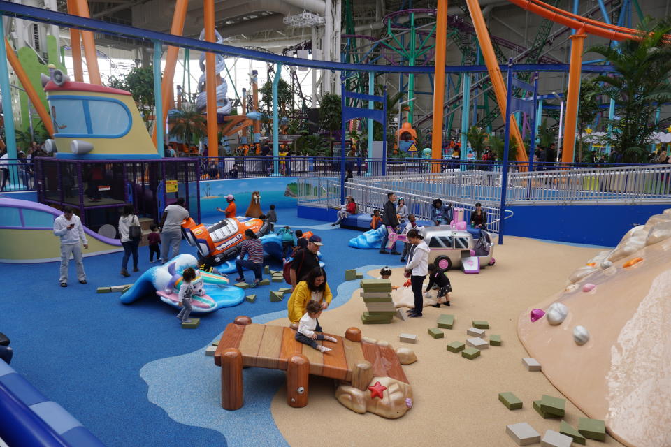 Toddlers play with their parents in an exploratory jungle gym at Nickelodeon Universe. 