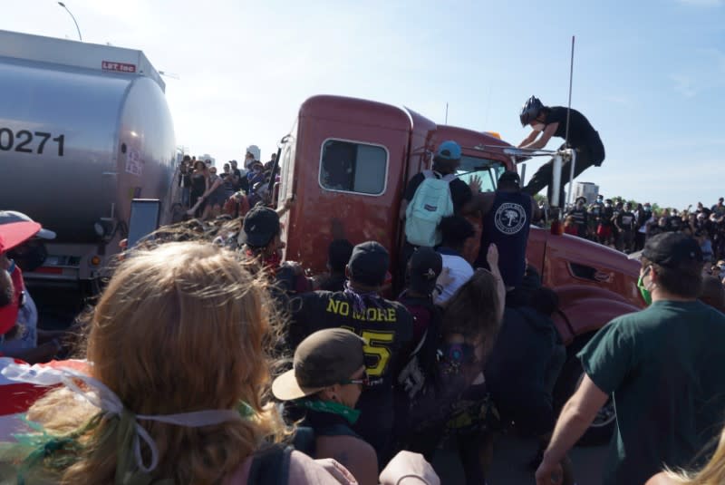 Protesters scale a truck that was driven into a rally