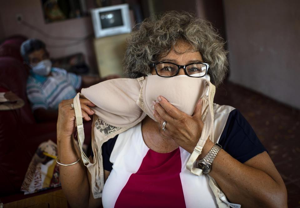 Idania Española, de 63 años, posa para una foto que muestra un sostén que adaptará en dos máscaras faciales, en medio de la propagación del nuevo coronavirus en Cojimar, Cuba, al este de La Habana, el martes 31 de marzo de 2020. (AP Foto / Ramon Espinosa )
