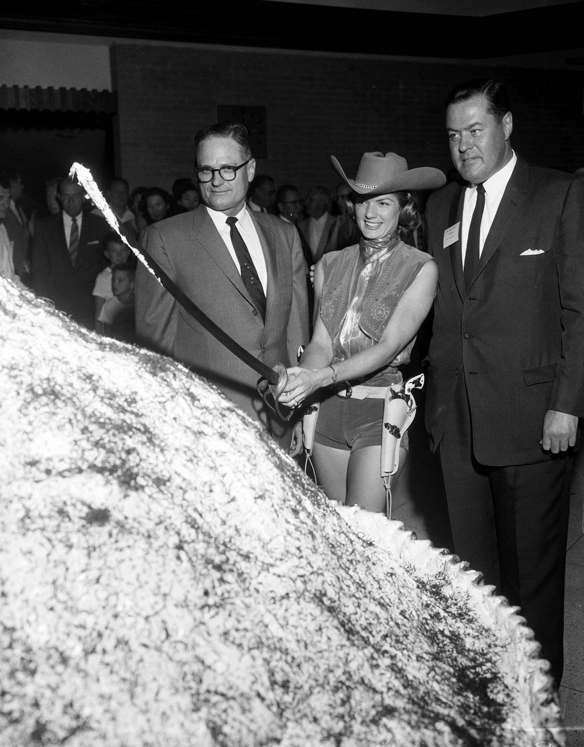 Aug. 27, 1957: Miss Turnpike June Prichard cuts a giant pie as J.C. Dingwall and H.S. Lokey look on.