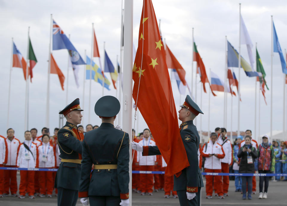 Russian soldiers raise China's flag as the Chinese Olympic delegation watches during a team welcoming ceremony before the 2014 Winter Olympics, Wednesday, Feb. 5, 2014, in Sochi, Russia. (AP Photo/Vadim Ghirda)