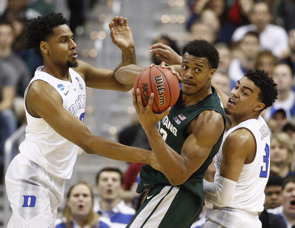 Michigan State forward Xavier Tillman (23) looks to pass the ball as he is covered by Duke center Marques Bolden (20) guard Tre Jones (3) during the first half of an NCAA men's East Regional final college basketball game in Washington, Sunday, March 31, 2019. (AP Photo/Patrick Semansky)