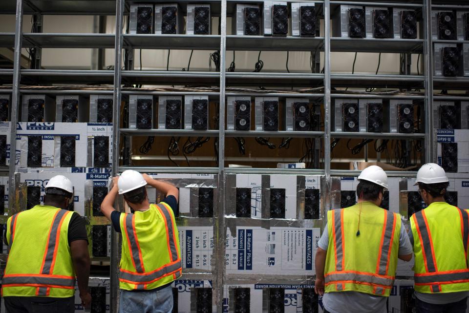 Workers install a new row of Bitcoin mining machines at the Whinstone US Bitcoin mining facility in Rockdale, Texas, on October 9, 2021. - The long sheds at North America&#39;s largest bitcoin mine look endless in the Texas sun, packed with the type of machines that have helped the US to become the new global hub for the digital currency. The operation in the quiet town of Rockdale was part of an already bustling US business -- now boosted by Beijing&#39;s intensified crypto crackdown that has pushed the industry west. Experts say rule of law and cheap electricity in the US are a draw for bitcoin miners, whose energy-gulping computers race to unlock units of the currency. 