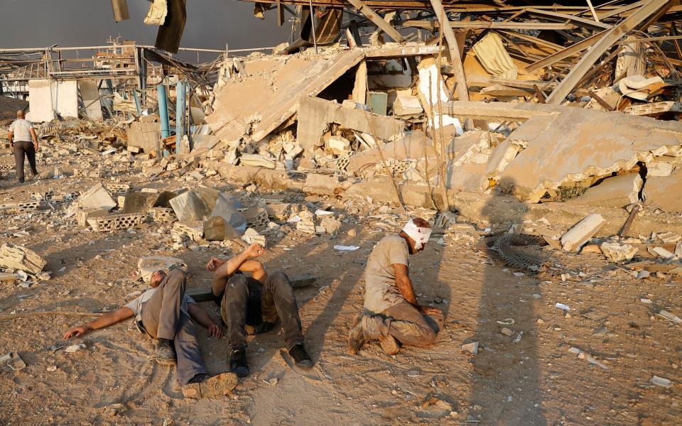 At the scene of the blast, injured men wait for help - AP