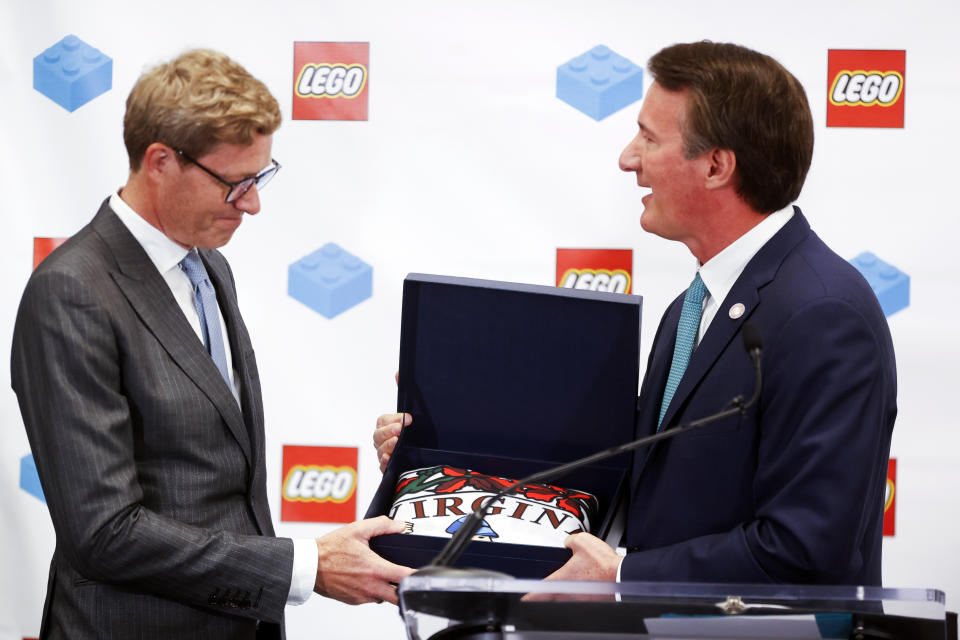 Virginia Gov. Glenn Youngkin presents a Virginia State flag to Lego Group CEO Niels Christiansen during a news conference at the Science Museum of Virginia, Wednesday, June 15, 2022 in Richmond, Va. The Danish toy company said Wednesday it plans to invest more than $1 billion over 10 years to build a new factory in Virginia and to enlarge an existing factory in Mexico. (Shaban Athuman/Richmond Times-Dispatch via AP)