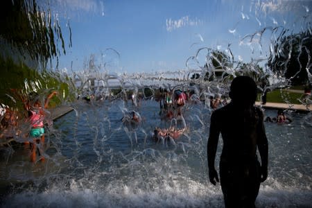 People cool off in a water feature in the Navy Yard neighborhood during a heat wave in Washington