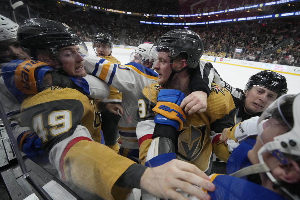 Vegas Golden Knights center Ivan Barbashev (49) and Vegas Golden Knights center Jack Eichel (9) fight with Buffalo Sabres during the second period of an NHL hockey game Friday, Dec. 15, 2023, in Las Vegas. (AP Photo/John Locher)