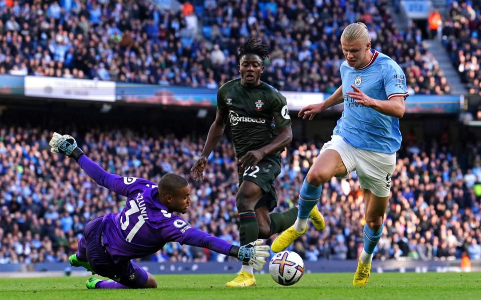 Southampton goalkeeper Gavin Bazunu saves at the feet of Manchester City's Erling Haaland during the Premier League match at the Etihad Stadium, Manchester