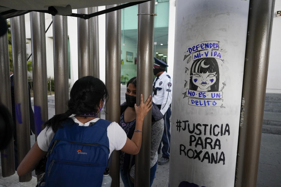 FILE - Roxana Ruiz, behind the gate, speaks from inside the court complex on the day of her court hearing where she is charged with killing her attacker in Chimalhuacan, State of Mexico, Mexico, April 18, 2022. Ruiz, who killed a man defending herself when he attacked and raped her in 2021 was sentenced to more than six years in prison, a decision her legal defense called “discriminatory” and vowed to appeal Tuesday, May 16, 2023.(AP Photo/Eduardo Verdugo, File)