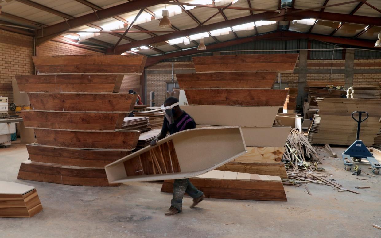 A worker carries a coffin at a manufacturing plant in Johannesburg, South Africa, in May  - Siphiwe Sibeko/Reuters