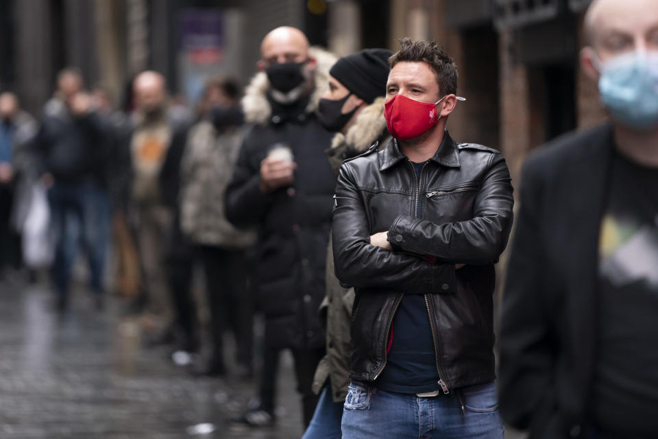 Members of the entertainment industry stand on Matthew Street in Liverpool, England, Monday Oct. 12, 2020, during a show of support for the hard hit sector as Prime Minister Boris Johnson lays out a new three-tier alert system for England. The British government is set to announce new restrictions on business and socializing in major northern England cities with high infection rates, under a plan to put areas into three tiers. (AP Photo/Jon Super)