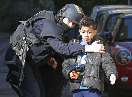 A French police officer speaks to a child as he secures an access to a school at the Castellane housing area in Marseille, February 9, 2015. Hooded gunmen armed with Kalashnikov rifles fired on police in the French city of Marseille, where French Prime Minister was paying a visit on Monday, a police source said. REUTERS/Jean-Paul Pelissier