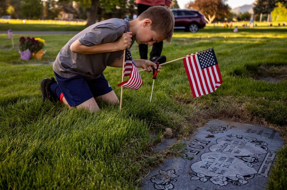 Volunteer Tate Cocciniglio, 11, places a flag at a marker at Larkin Sunset Gardens Cemetery in Sandy on Thursday, May 27, 2021. More than 200 youth volunteers from around the Salt Lake Valley honored military veterans for Memorial Day by placing 3,000 American flags on the graves of service members. In addition, they swept and polished headstones and helped beautify cemetery grounds. | Annie Barker, Deseret News