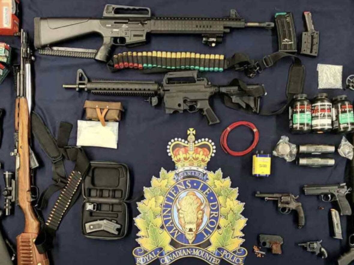 A Codiac Regional RCMP photo shows items seized during the noon-hour raid Thursday, including homemade pipe bombs, bomb-making materials, a crossbow, ammunition and firearms. (Codiac Regional RCMP - image credit)
