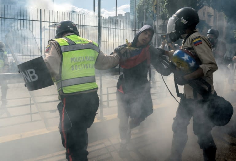 Riot policemen struggle with a demonstrator during a protest against the government of President Nicolas Maduro in Caracas on May 20, 2017