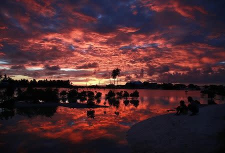 Villagers watch the sunset over a small lagoon near the village of Tangintebu on South Tarawa in the central Pacific island nation of Kiribati May 25, 2013. REUTERS/David Gray