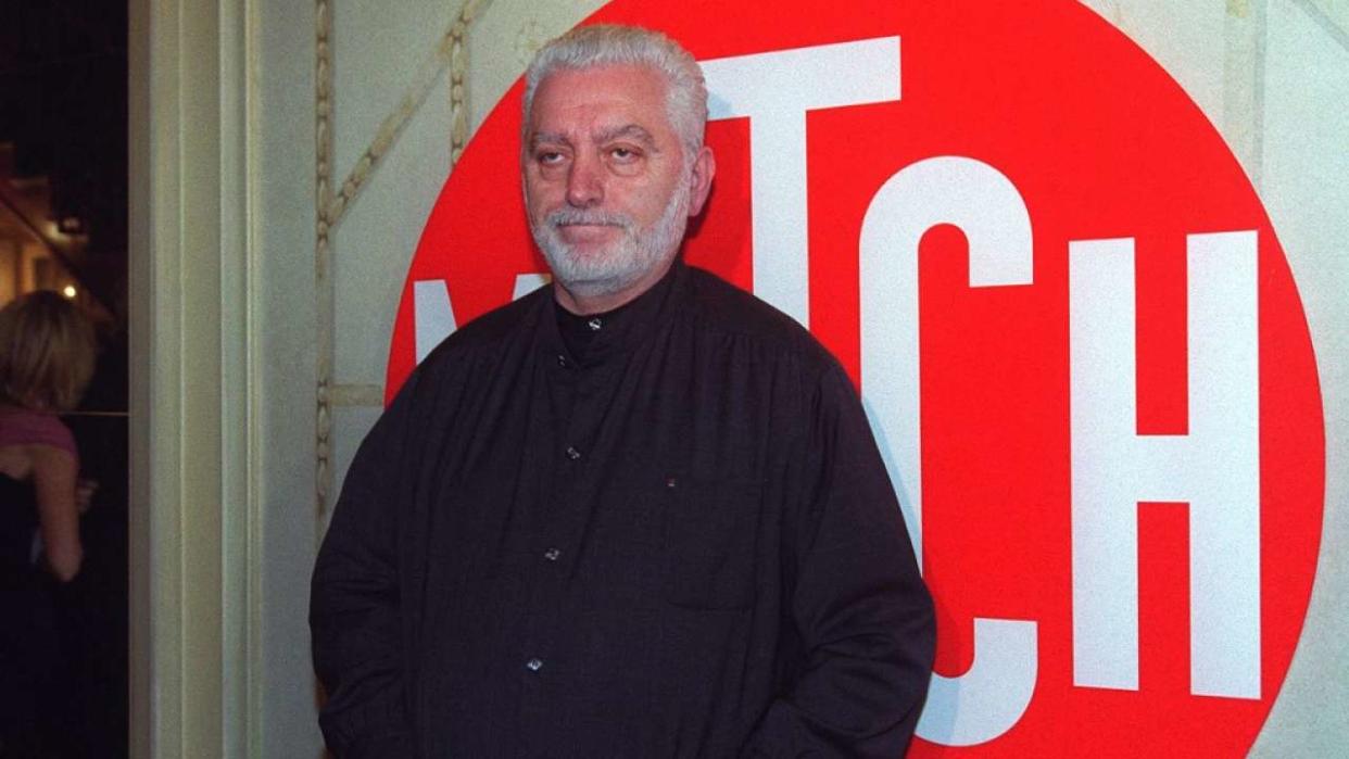 Le couturier Paco Rabanne, pose, le 10 décembre 2001 à Paris, devant le logo de la chaîne Match TV, lors de la cérémonie d'inauguration, dans un restaurant parisien. La dernière-née du groupe Lagardère Média est la version télévisuelle et 