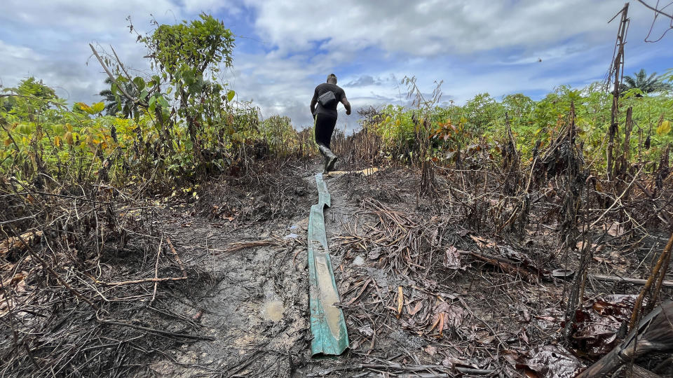 A man walk past an area of an illegal refinery in Emohua, Niger Delta Nigeria Tuesday, Oct. 3, 2023. At least 15 people have been confirmed dead in a fire outbreak after an illegal oil refinery site exploded in Nigeria's Niger Delta region, locals said Tuesday, with the death toll likely much higher with many bodies completely burned. (AP Photo)