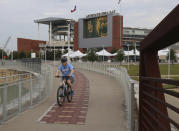 A bicyclist makes his way past Baylor University's McLane Stadium, Thursday, Sept. 17, 2020, in Waco, Texas. Baylor’s season opener against Houston, scheduled less than a week ago, was one of two FBS NCAA college football games postponed Friday, Sept. 18, 2020, the day before before they were supposed play. (Rod Aydelotte/Waco Tribune-Herald via AP)