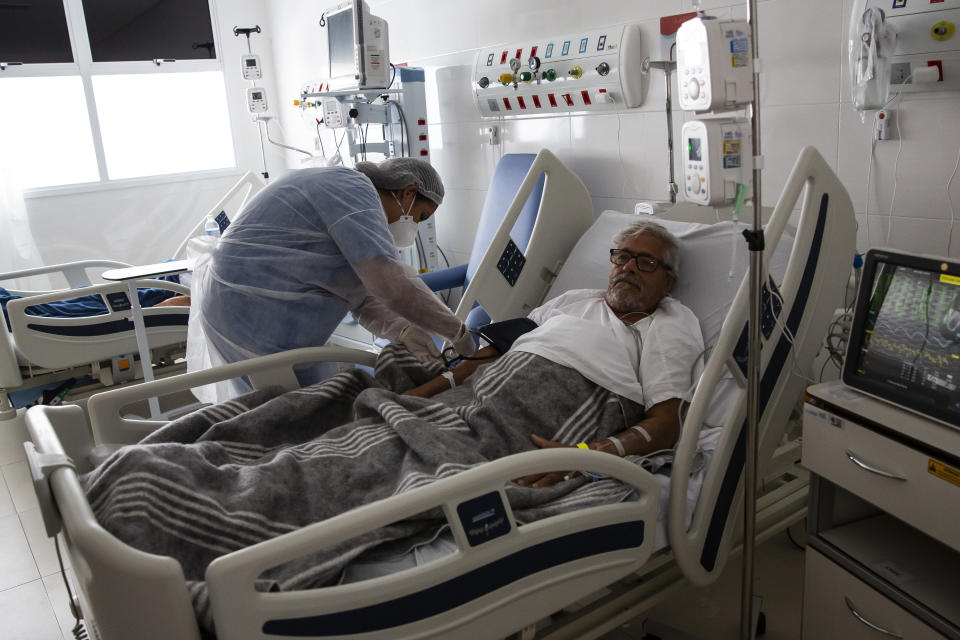 A nurse treats COVID-19 patient João Claudio Ribeiro, 70, at the Dr. Ernesto Che Guevara hospital in Marica, Brazil, Wednesday, Jan. 26, 2022. (AP Photo/Bruna Prado)