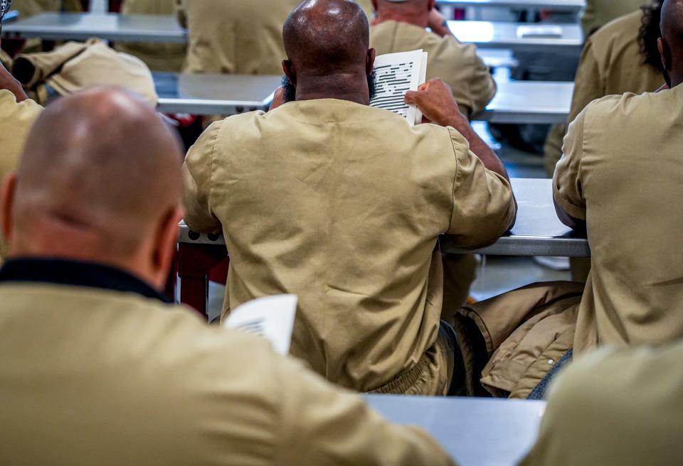 ACI inmates browse "Felon," a book of poetry by Reginald Dwayne Betts, who visited the prison.