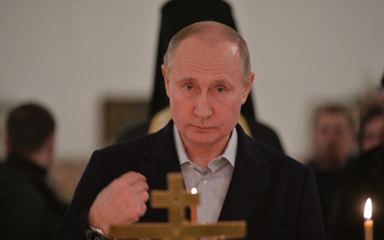 Vladimir Putin crosses himself during an Epiphany service at a monastery last week - Barcroft Media