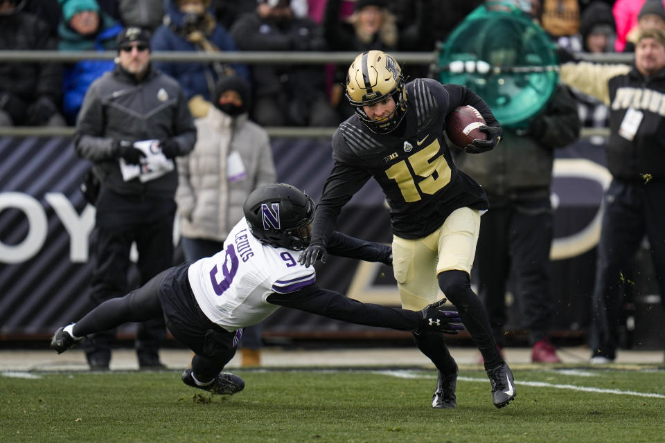 Purdue wide receiver Charlie Jones (15) breaks the tackle of Northwestern defensive back Jeremiah Lewis (9) on his way to a touchdown during the first half of an NCAA college football game in West Lafayette, Ind., Saturday, Nov. 19, 2022. (AP Photo/Michael Conroy)