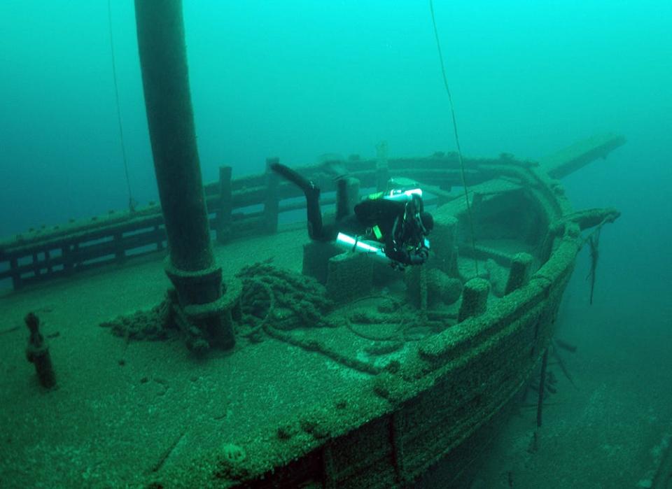 A diver swims over the two masted schooner Walter B. Allen, which sunk in 1880. The shipwreck sits on the bottom of Lake Michigan in the Wisconsin Shipwreck Coast National Marine Sanctuary.