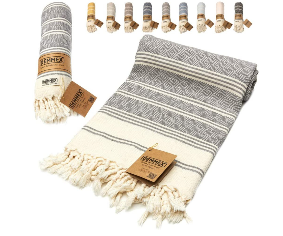 A rolled up navy and cream Turkish towel with tassels infront of a white background.