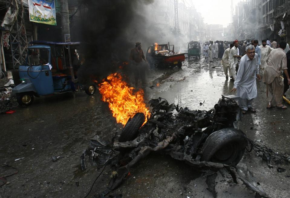 Security officials, rescue workers and residents gather at the site of a bomb attack in Peshawar September 29, 2013. Twin blasts in the northwestern Pakistan city of Peshawar killed 33 people and wounded 70 on Sunday, a week after two bombings at a church in the frontier city killed scores, police and hospital authorities said. REUTERS/Khuram Parvez (PAKISTAN - Tags: POLITICS CIVIL UNREST CRIME LAW)