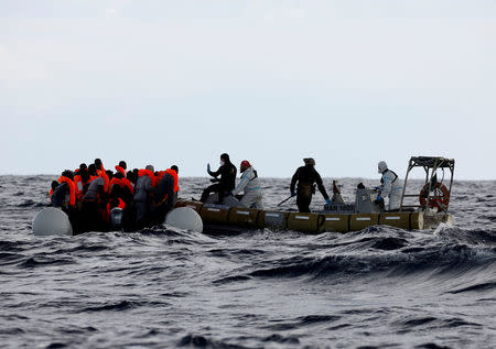 FILE PHOTO: Italian Navy personnel rescue migrants from their overcrowded raft, as lifeguards from the Spanish NGO Proactiva Open Arms rescue all 112 on aboard, including two pregnant women and five children, as it drifts out of control in the central Mediterranean Sea, some 36 nautical miles off the Libyan coast January 2, 2017. REUTERS/Yannis Behrakis/File Photo