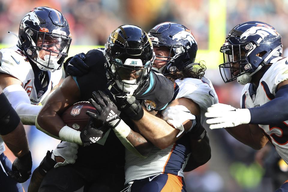 Denver Broncos linebacker Josey Jewell (47), sercond right, tackles Jacksonville Jaguars running back Travis Etienne Jr. (1) during the NFL football game between Denver Broncos and Jacksonville Jaguars at Wembley Stadium in London, Sunday, Oct. 30, 2022. (AP Photo/Ian Walton)