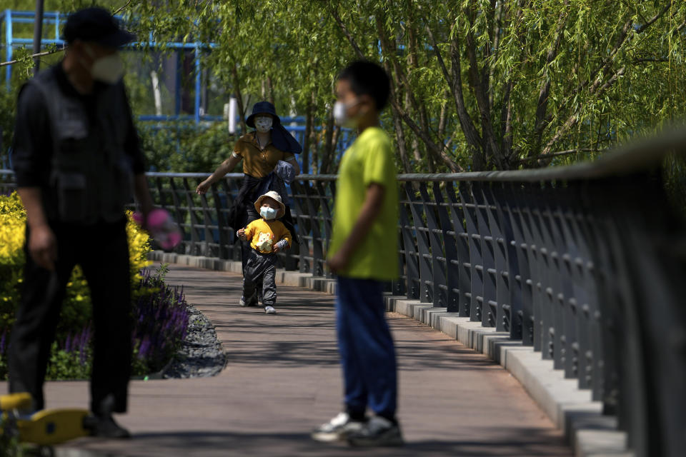 Residents wearing face masks bring their children tour along a canal on Sunday, May 15, 2022, in Beijing. (AP Photo/Andy Wong)
