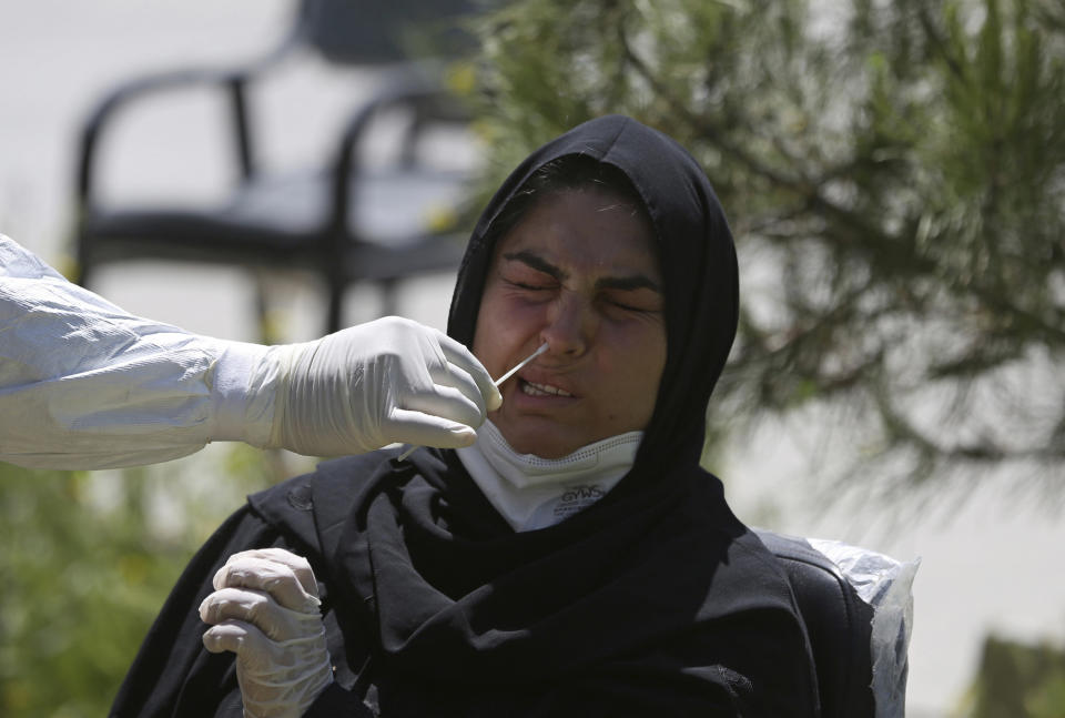 FILE - In this May 18, 2020, file, photo, an Afghan lab technician takes a sample with a swab to test a woman for the coronavirus at the Afghan-Japan Communicable Disease Hospital, Kabul's main facility for coronavirus testing and treatment, in Kabul, Afghanistan. A prominent international aid organization warned Tuesday, June 2, 2020 that Afghanistan is on the brink of a humanitarian disaster because the government is unable to test at least 80% of possible coronavirus cases. (AP Photo/Rahmat Gul, File)