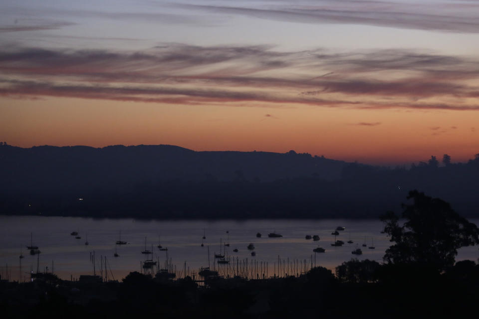 The Tiburon Peninsula remains dark from a power blackout Monday, Oct. 28, 2019, in this view from Sausalito, Calif. Millions of people in Northern California are on track to have lights come back on, but some may not be restored before another round of strong winds threaten to damage power lines and spark fires. Electricity is expected to begin being restored by Monday, though Pacific Gas & Electric Co. warned it might cut power again as soon as Tuesday with a forecast of strong winds expected to last until Wednesday. (AP Photo/Eric Risberg)